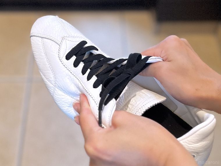 黒い靴紐が付いた白いスニーカーを引っ張っている様子