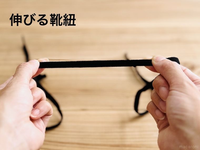 黒い靴紐を両手で引っ張っている様子