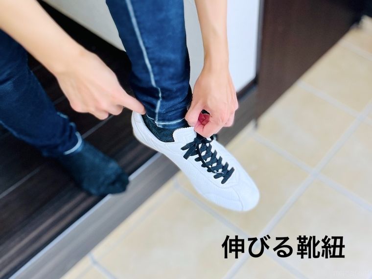 立ったまま白いスニーカーを履いている様子