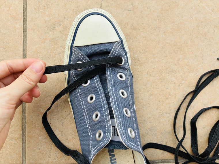 スニーカーの穴に靴紐を通している
