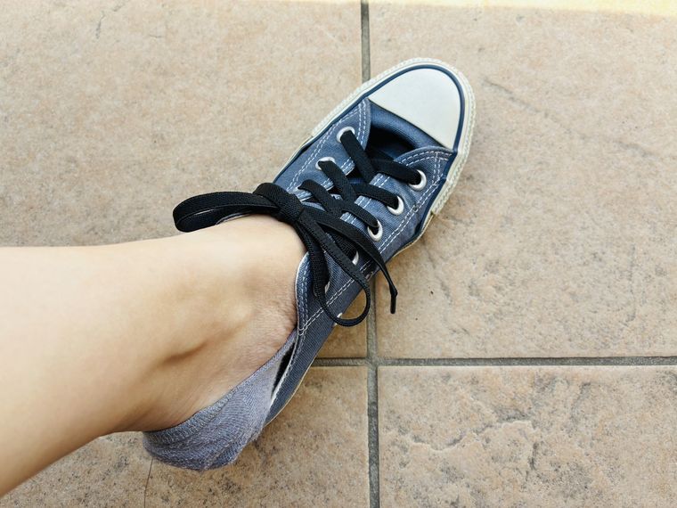 伸びる靴紐付きのスニーカーを脱いでいる