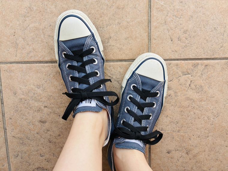 伸びる靴紐付きのスニーカーを履いた足