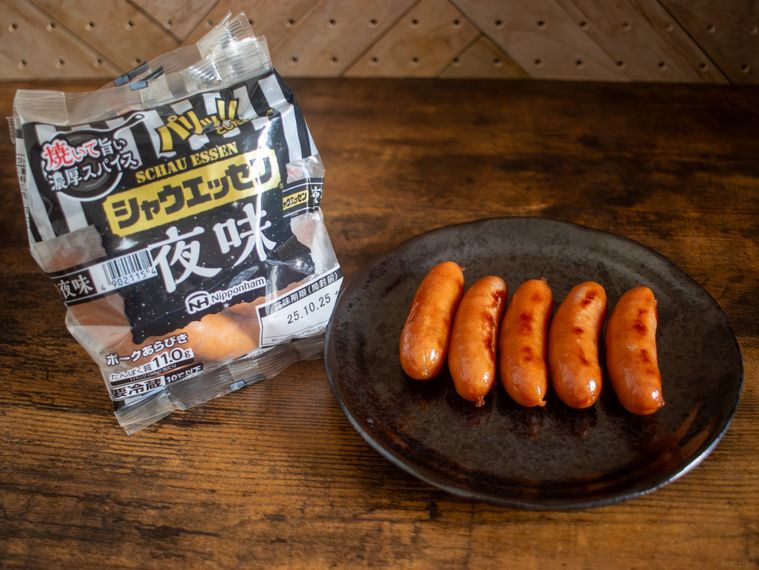 シャウエッセン夜味のパッケージと黒い丸皿に盛り付けた5本のソーセージがテーブルに並んでいる