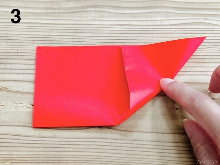 半分に折った折り紙の角を畳んでいる様子