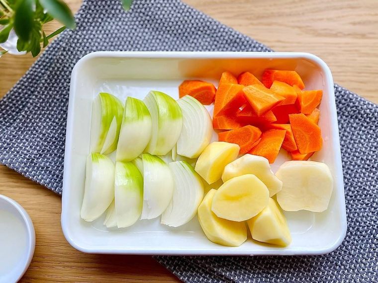 白いバットに並んだじゃがいもやにんじんなどのカットされた野菜