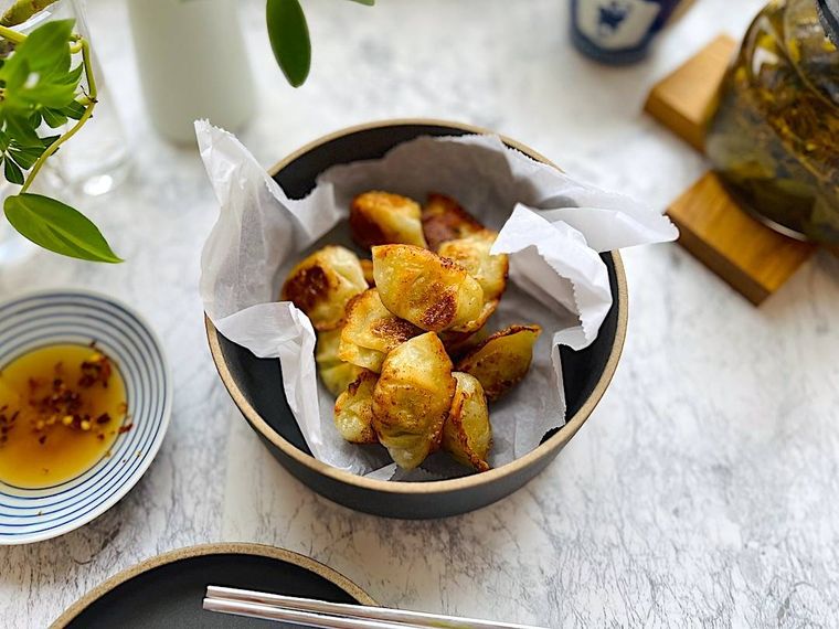 ペーパーを敷いた器に盛った揚げ焼きの水餃子、小皿に入ったタレ、中国茶