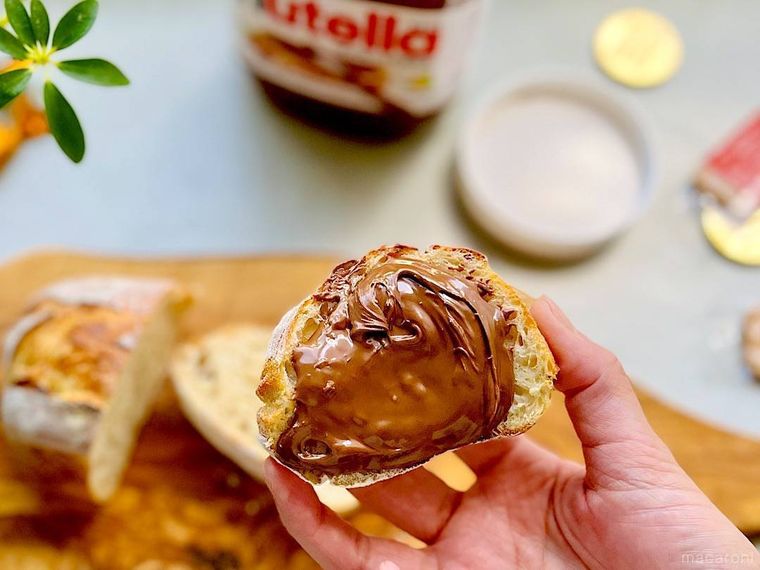 手で持ったコストコのヌテラを塗ったパン