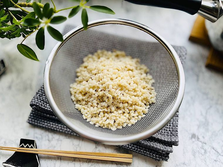 ゆでてざるにとったコストコのもち麦、グレーの布巾、箸と箸置き