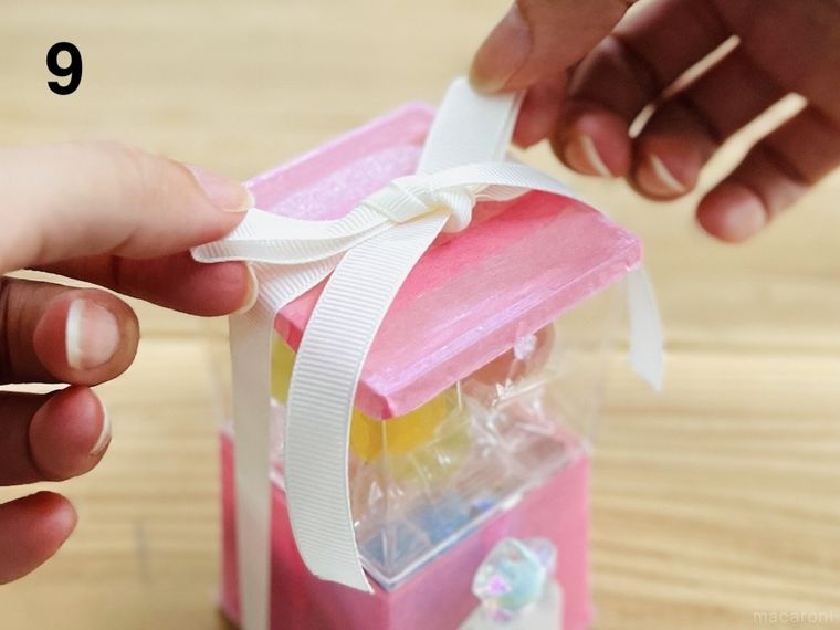 デザートクリアカップで作ったガチャ風のギフトにリボンを結んでいる様子