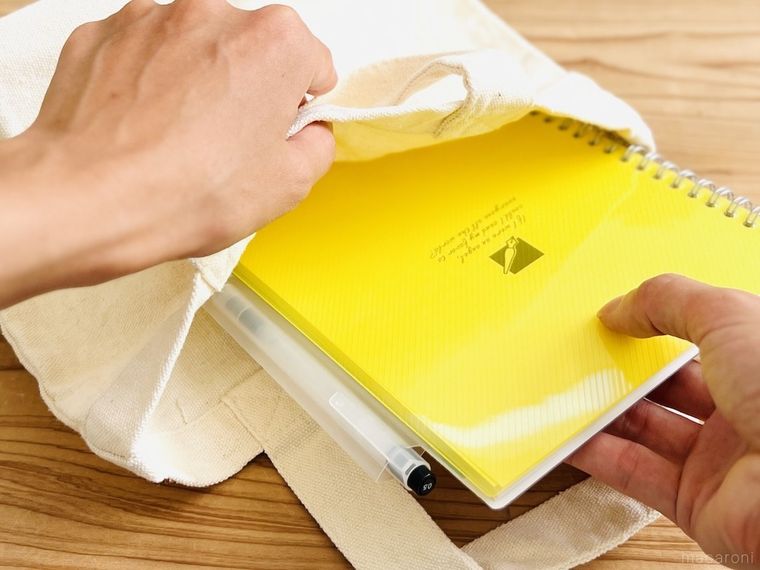 ペンホルダーが付いた黄色いノートをバッグにしまっている様子