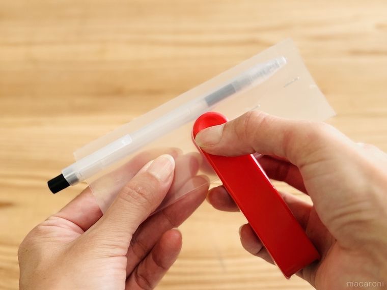 ボールペンを引っ掛けたクリアファイルにホッチキスを留めている様子