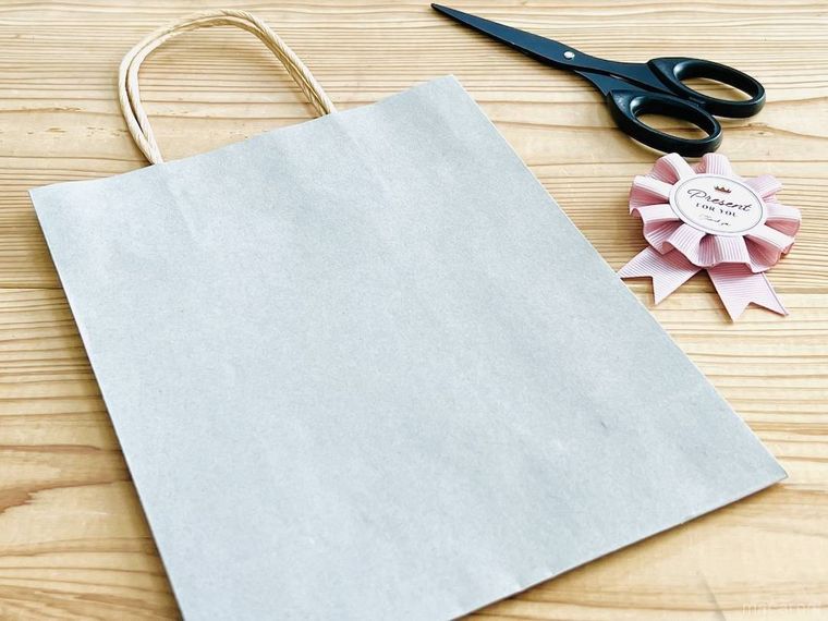 灰色の紙袋、ハサミ、ピンク色の飾り