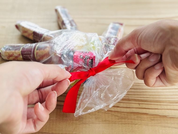 お菓子を詰めた使い捨て手袋にリボンを結んでいる様子