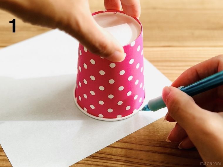 折り紙に紙コップを当ててシャーペンで縁取りをしている様子