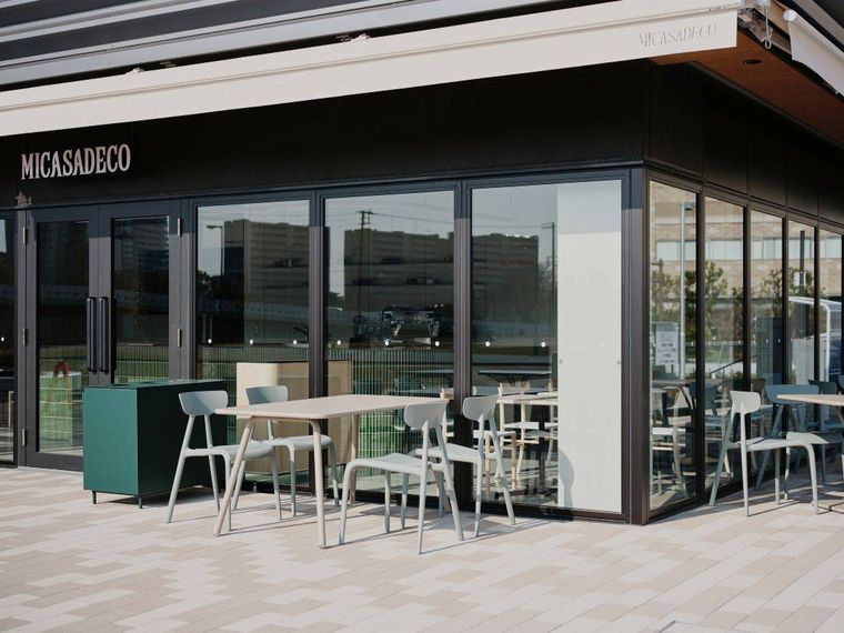 店頭にテーブルセットが設置されたガラス張りのミカサデコ ザ パークの外観