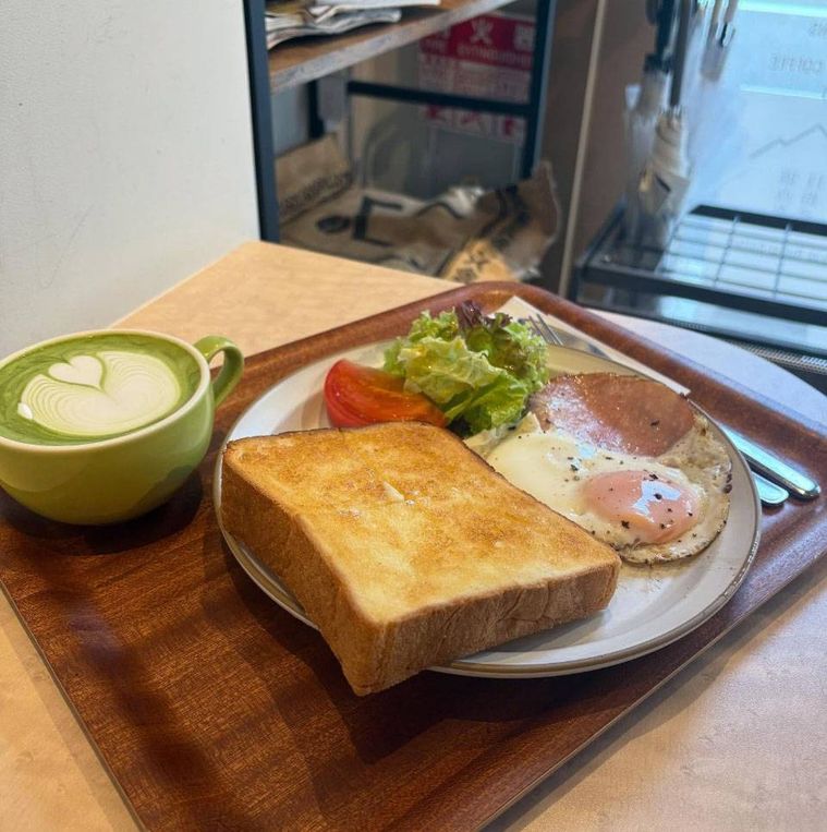 木のトレイにのせられたハムエッグトーストと抹茶ラテ