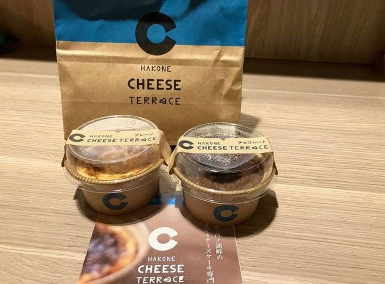 紙袋の前に置かれた箱根チーズテラスのカップ入り バスクチーズケーキ2個