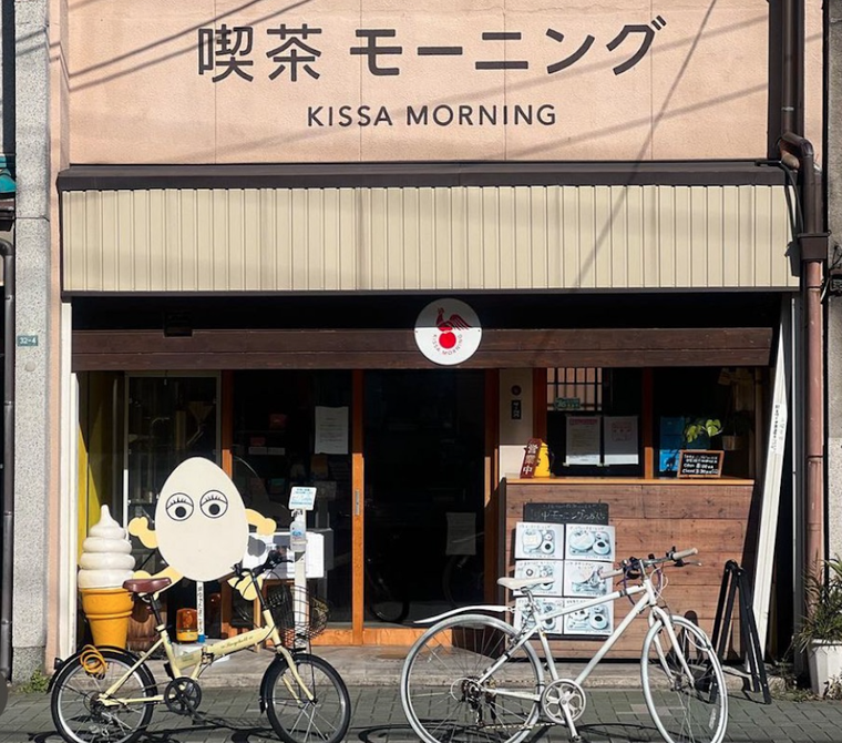 黒い文字で屋号、卵のキャラクター、2台の自転車とソフトクリームの模型