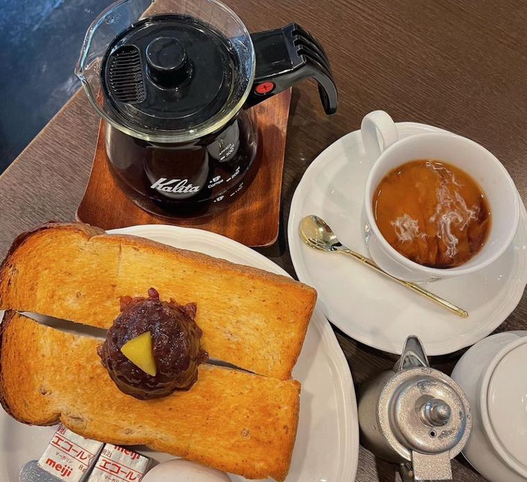 白いお皿にのる小倉トーストとバター2個、ゆで卵。白いカップのコーヒー