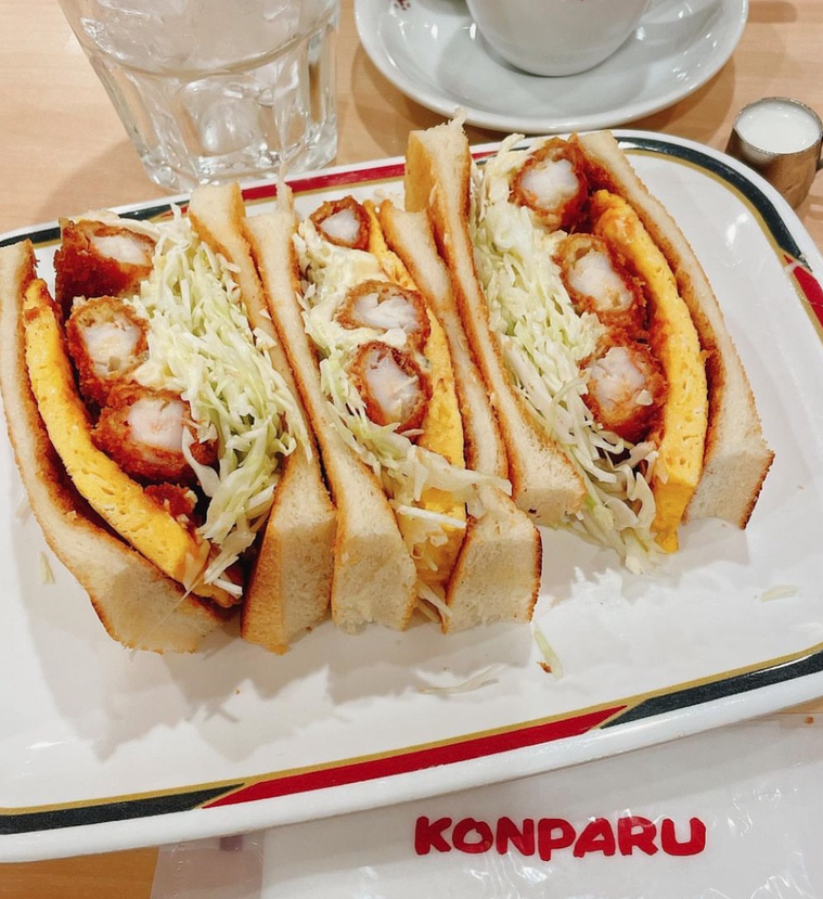 白いトレーにのったエビフライサンド、グラスに入ったお水、アルファベットでKONPARUと書かれたおしぼり