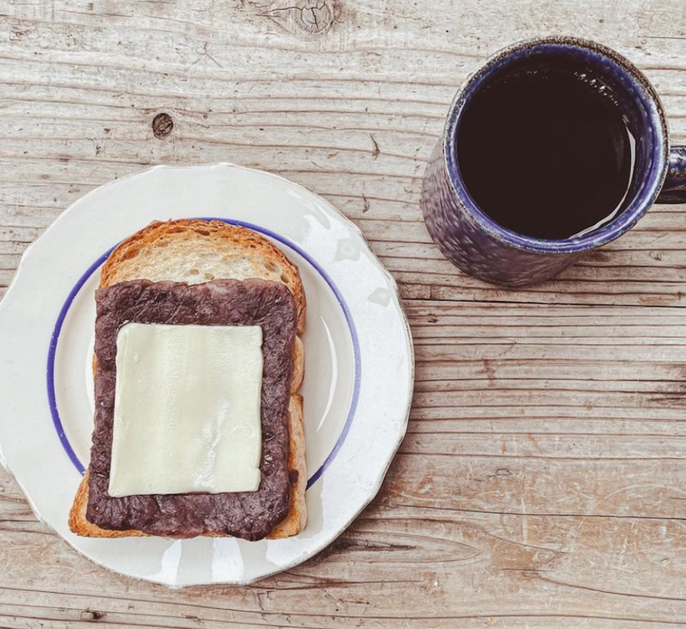 木のテーブルに置かれた白いお皿にのる小倉トースト、青いコーヒーカップのコーヒー