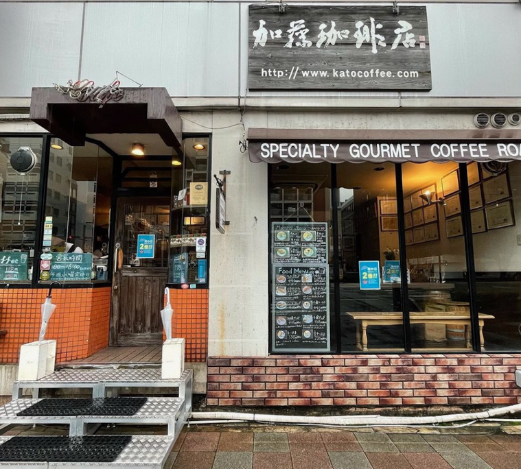 扉の前に踏み台、ガラス張りの外観、白い文字で屋号が書かれた木製の看板