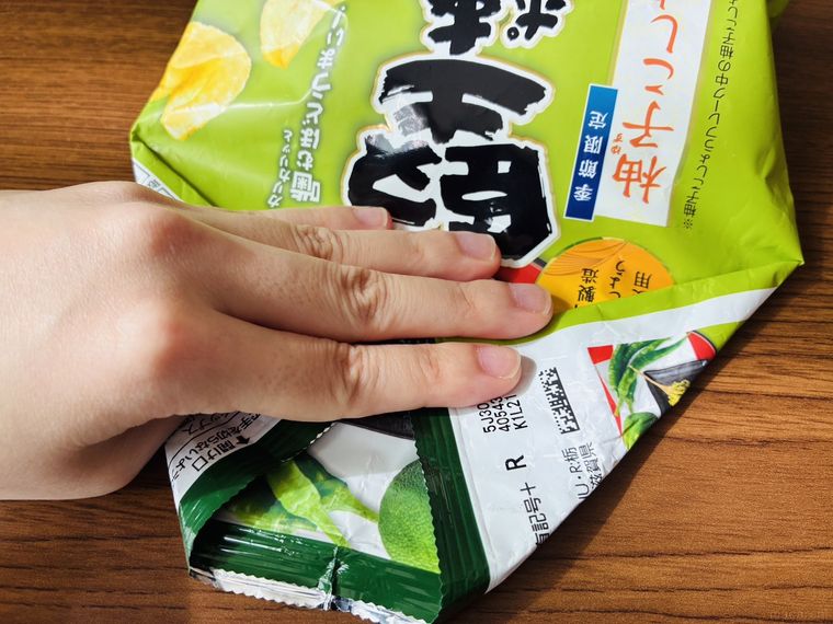ポテチ袋の空気を抜きながら口を折っている