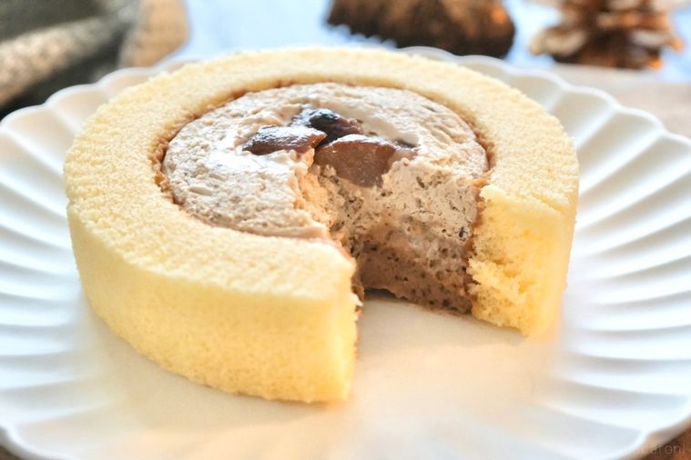 木のカッティングボードと白い皿にのった渋皮栗のプレミアムロールケーキの断面