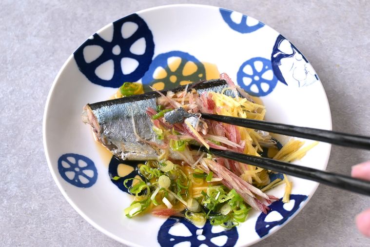 薬味をのせたゆでさんまの身を箸で摘む様子