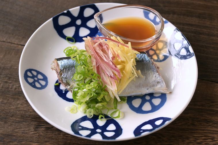 れんこん柄の丸皿に、薬味をたっぷりのせたゆでさんまが盛り付けられていてポン酢しょうゆが添えてある
