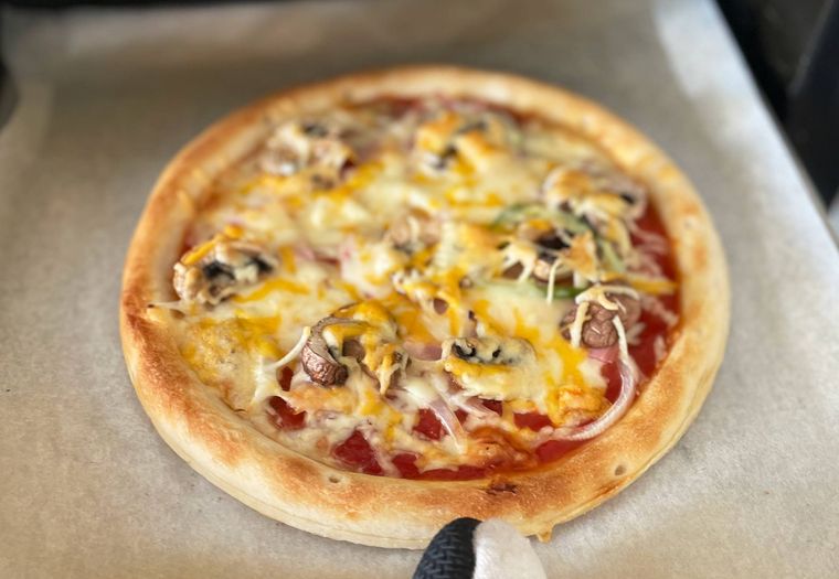 オーブンで焼き上がったピザを取り出すところ