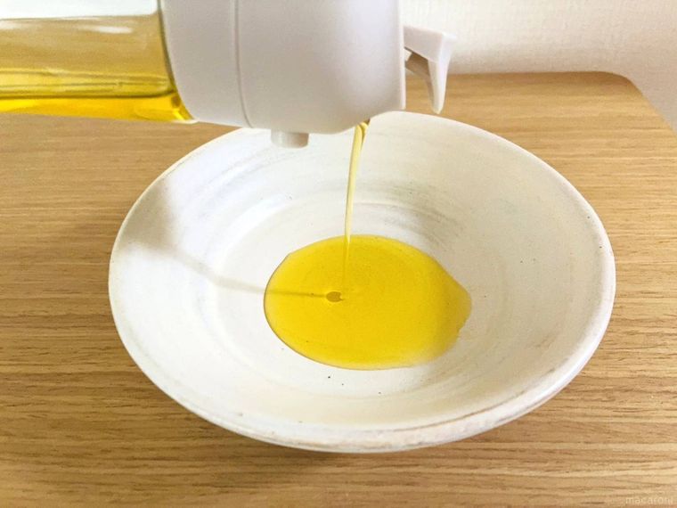 オイルスプレーボトルから皿に油を注いでいる