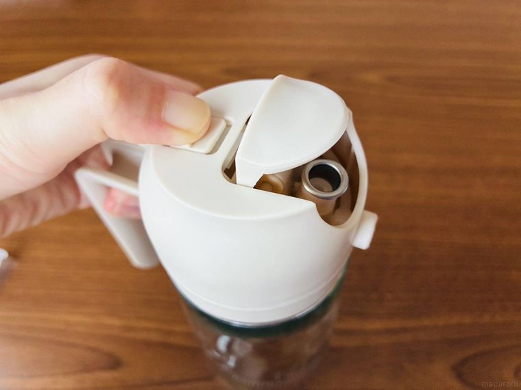 オイルスプレーのボタンをスライドさせてフタを開けている