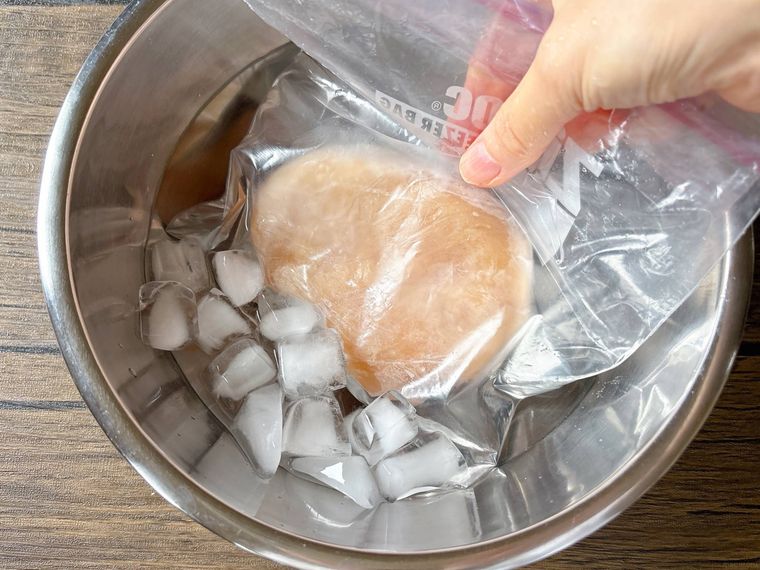 フリーザーバッグに入った冷凍肉を氷水で解凍する様子