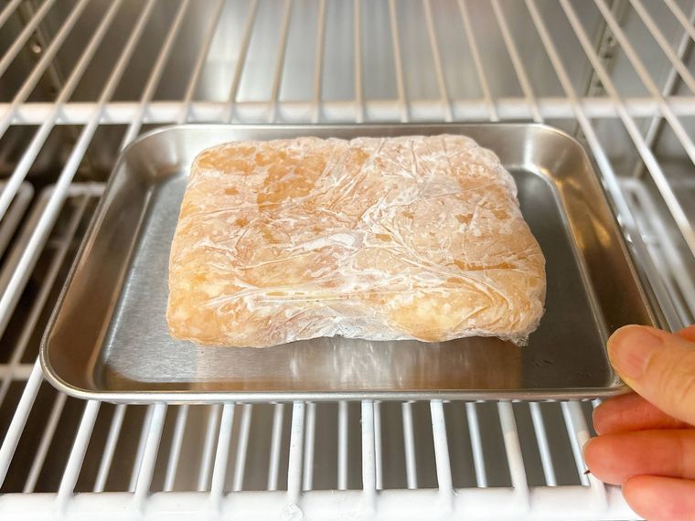 金属トレーにのせた冷凍肉を冷蔵庫に入れる様子