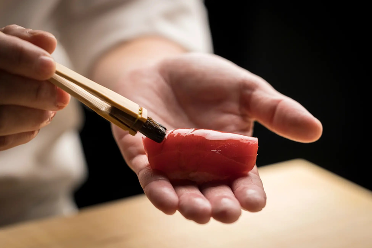 鮨にハケで醤油を塗っている