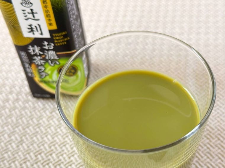 グラスに注がれた明治の辻利お濃い抹茶ラテ210mlとパッケージが並んでいる様子