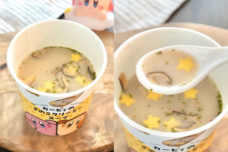 木のカッティングボードにのった黄色いカップスープを白いスプーンで食べる様子