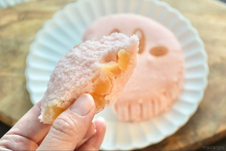 木のカッティングボードと白い皿にのったカービィのりんご蒸しパンを手に持つ様子