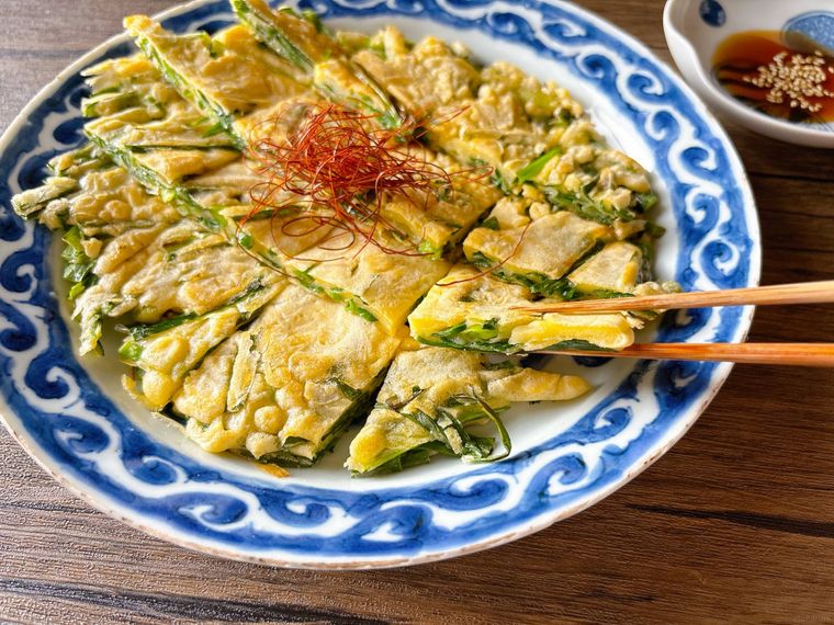 青色の皿に盛られたニラチヂミを箸上げする様子