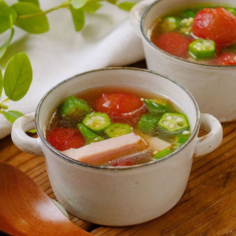 手付きの白色のカップに入ったオクラとトマトのコンソメスープ