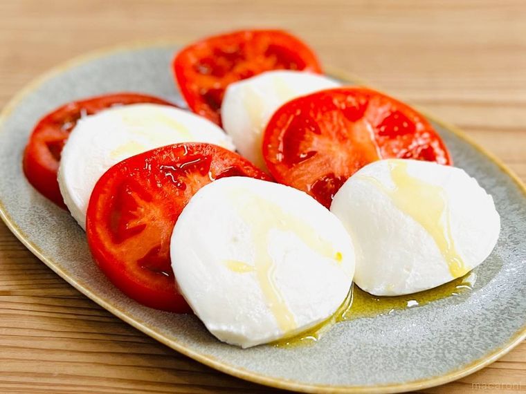 トマトとモッツァレラチーズにオリーブオイルをかけた様子