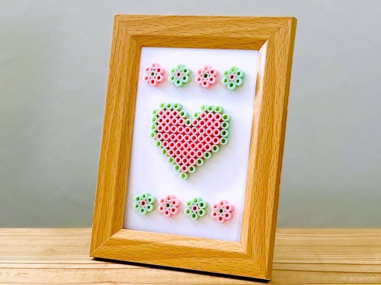 アイロンビーズで作ったハート型と花型の作品を額に入れた様子