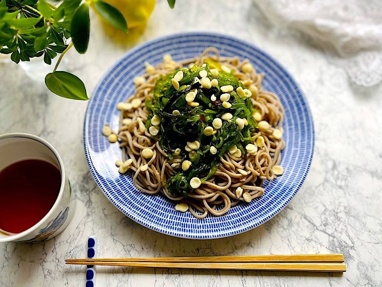 ブルーの皿に盛ってコストコのごまわかめをトッピングした蕎麦、箸、蕎麦猪口
