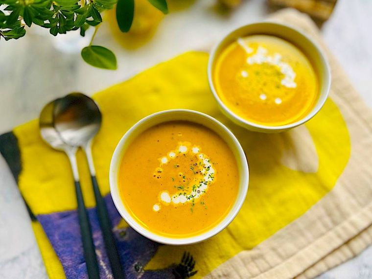 黄色のキッチンタオルの上に並んだ2皿のポタージュ、スプーン