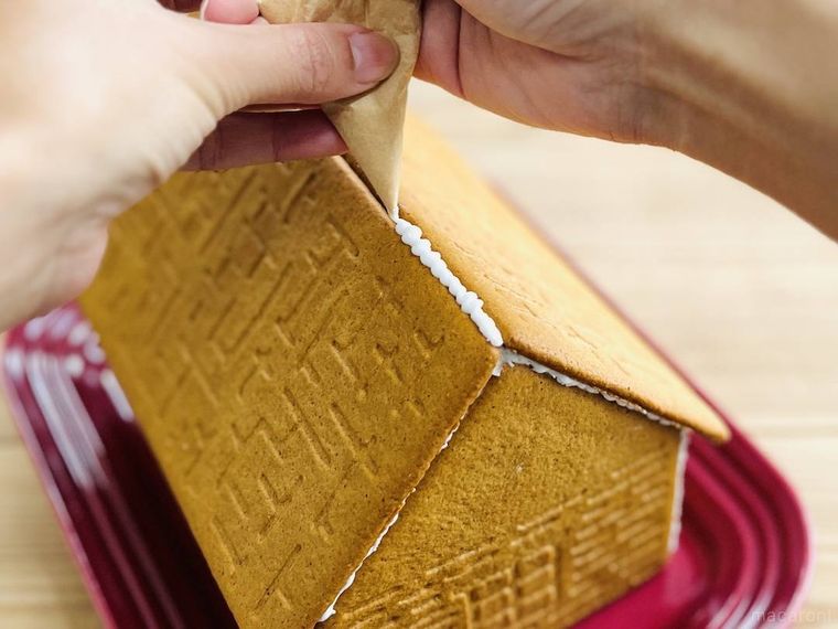 ビスケットにアイシングを絞ってお菓子の家を作っている様子