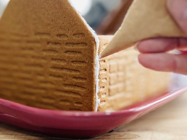 ビスケットにアイシングを絞ってお菓子の家を作っている様子