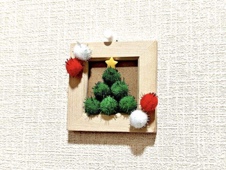 ポンポンで作るクリスマスツリーが壁に飾られている