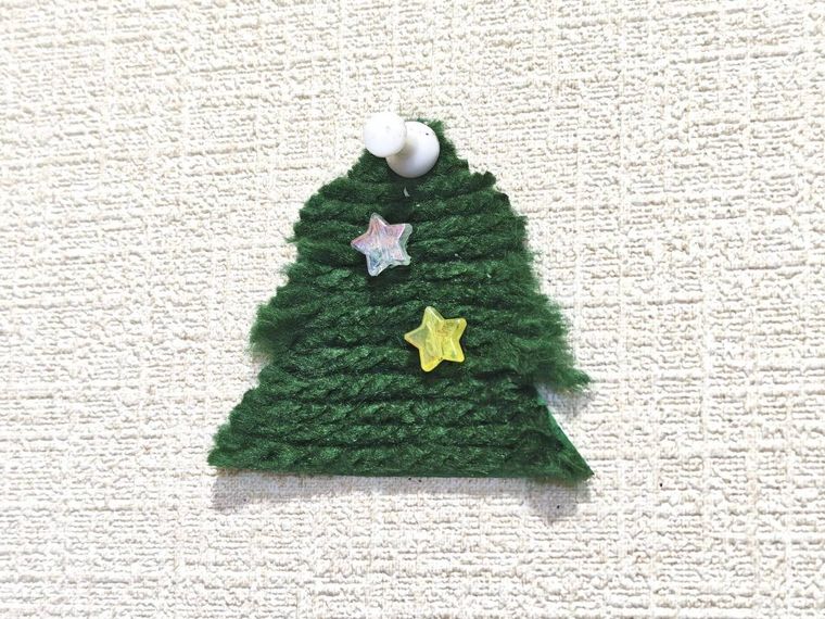 毛糸で作るもこもこミニツリーを壁に貼り付けている