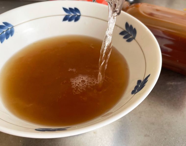 濃縮タイプのラーメンスープにお湯を注いでいる写真